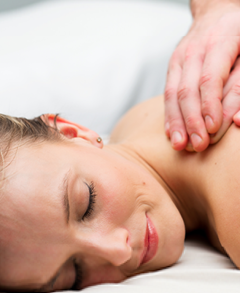 Woman lying on massage table having back massaged with deep tissue treatment