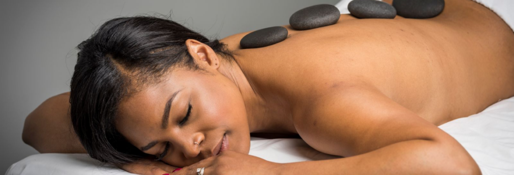 Woman lying on massage table with hot stone treatment